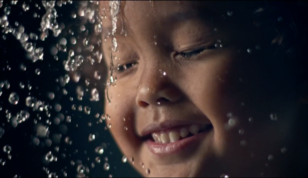 Water flowing on young boys face in super slow motion
