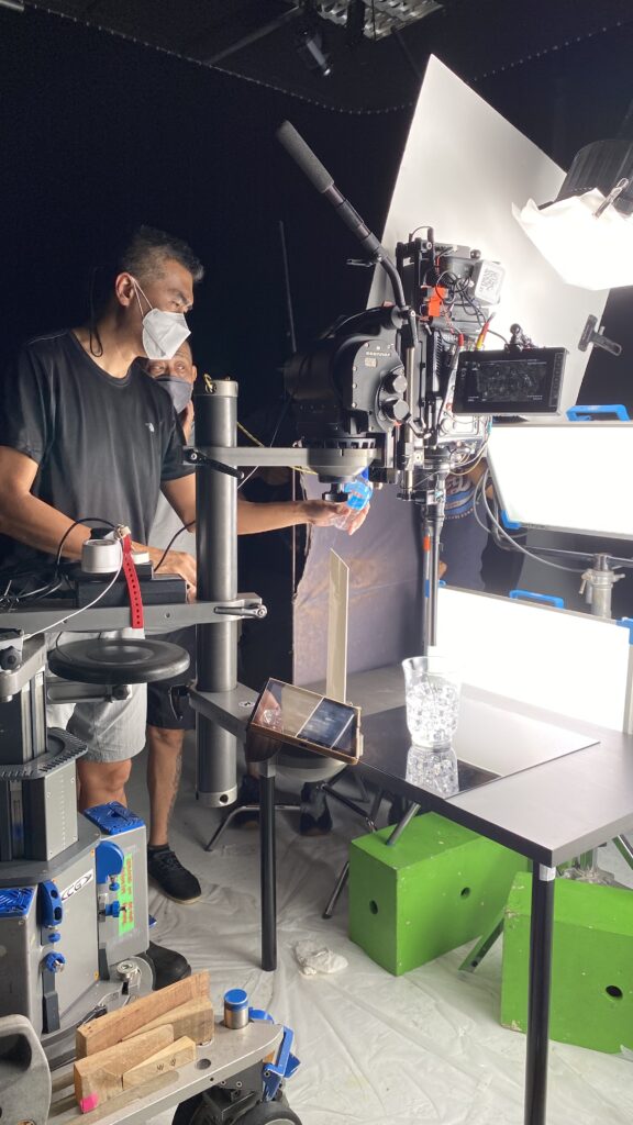 Cinematographer operating a high-speed camera beside studio lighting and production equipment